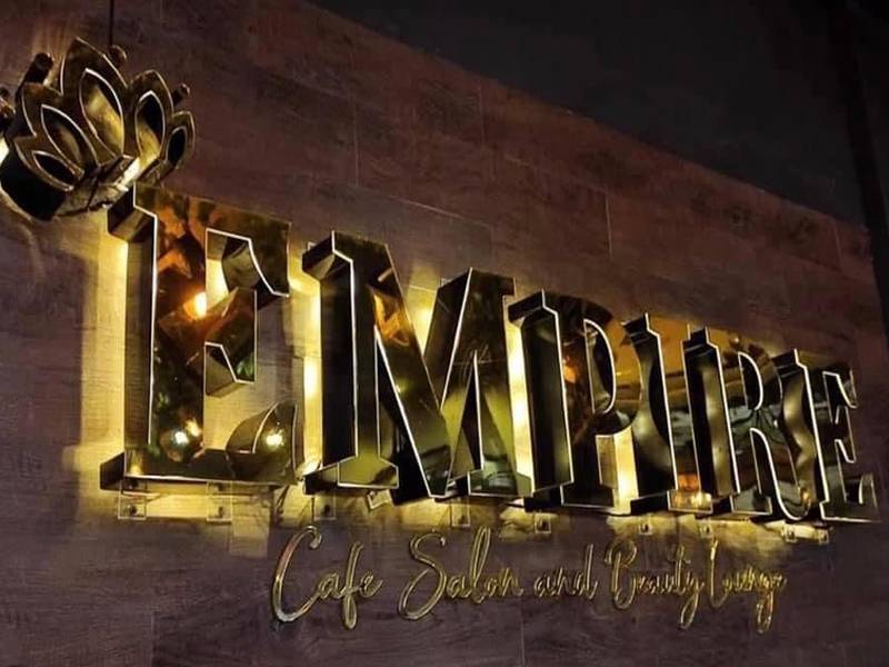 Empire cafe and salon 3D sign, lit gold on a dark wall